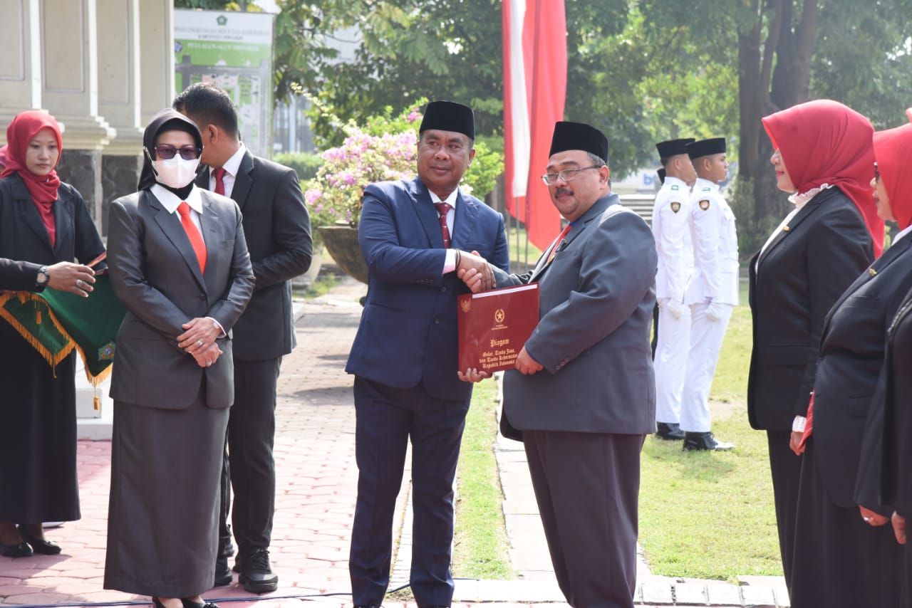 SERAHKAN - Pjs Bupati Sidoarjo, Muhammad Isa Ansori menyerahkan penghargaan usai upacara Hari Pahlawan berupa Satyalencana Karya Satya dari Presiden RI yang diterima PNS Pemkab Sidoarjo di Alun - Alun Sidoarjo, Minggu (10/11/2024).