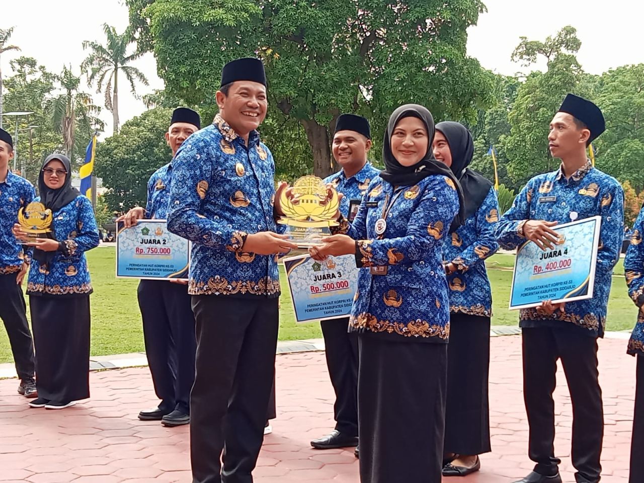 JUARA - Dinkes Pemkab Sidoarjo meraih juara umum dalam berbagai perlombaan memperingati HUT KORPRI ke 53 dari berbagai Organisasi Perangkat Daerah (OPD) hadiah diserahkan saat upacara di Alun-Alun, Sidoarjo, Jumat (29/11/2024) pagi.