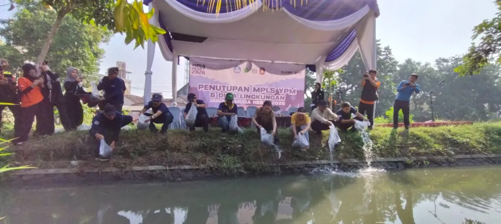 TEBAR BENIH - Secara simbolis Kepala SMK YPM 8 Sidoarjo Dr Kisyanto, SE M Pd bersama para guru dan tamu undangan melepas 18.000 benih ikan lele ke aliran sungai yang dibersihkan di Desa Sarirogo, Kecamatan Sidoarjo, Jumat (17/07/2026).