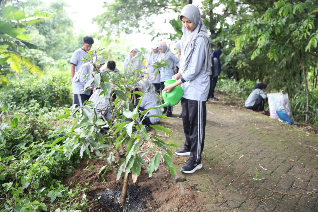 TANAM POHON - Kader Adiwiyata SMA Al Muslim menggelar kegiatan penanaman pohon di bantaran sungai Driyorejo Gresik bekerjasama dengan Ecoton dan masyarakat sekitar untuk menjaga keseimbangan lingkungan sungai, Sabtu (10/01/2026).