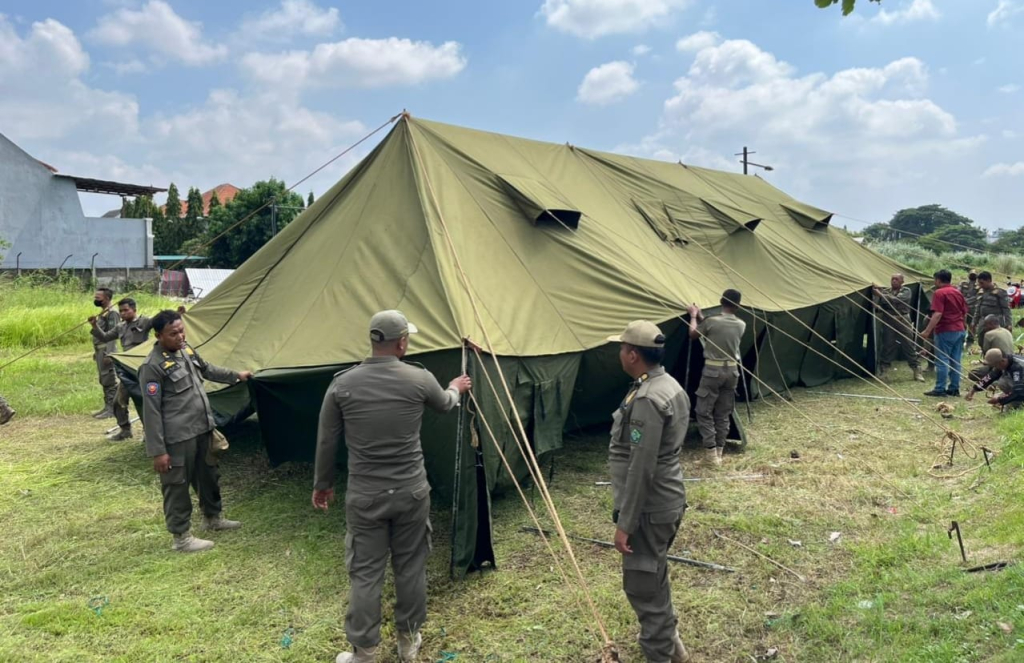 TENDA - Petugas Satpol PP Pemkab Sidoarjo memasang tenda di kawasan Perumahan Mutiara City untuk siaga pengamanan usai merobohkan tembok batas perumahan Mutiara Regency di Desa Banjarbendo, Kecamatan Sidoarjo, Sabtu (31/01/2026).