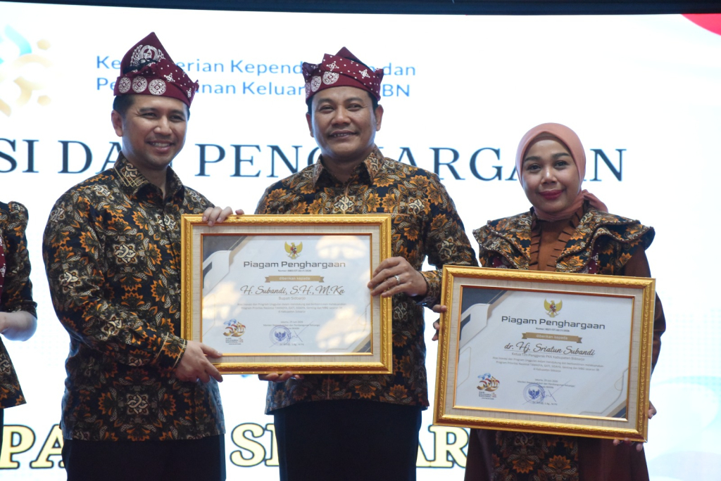 TERIMA - Bupati Subandi dan Ketua TP PKK Sriatun menerima penghargaan dari Kementerian Kependudukan dan Pembangunan Keluarga diserahkan Wagub Jatim Emil Elestianto Dardak di Puncak Peringatan Harganas ke 33 di Pendopo Agung Malang, Rabu (29/07/2026).