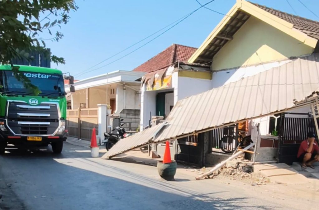 AMBRUK - Nasib naas menimpa Eka Trisnawati warga Desa Karangbong, Kecamatan Gedangan, Sidoarjo yang teras rumahnya di pinggir jalan desa roboh usai diserempet truk tangki berukuran besar yang mengangkut minyak, Minggu (26/07/2026) dini hari.