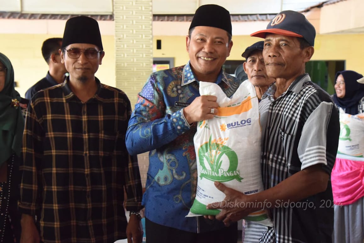 SERAHKAN - Plt Bupati Sidoarjo Subandi menyerahkan bantuan beras 10 kilogram dari pemerintah pusat untuk warga delapan desa di Kecamatan Balongbendo dan Kecamatan Tarik, Selasa (11/06/2024). 