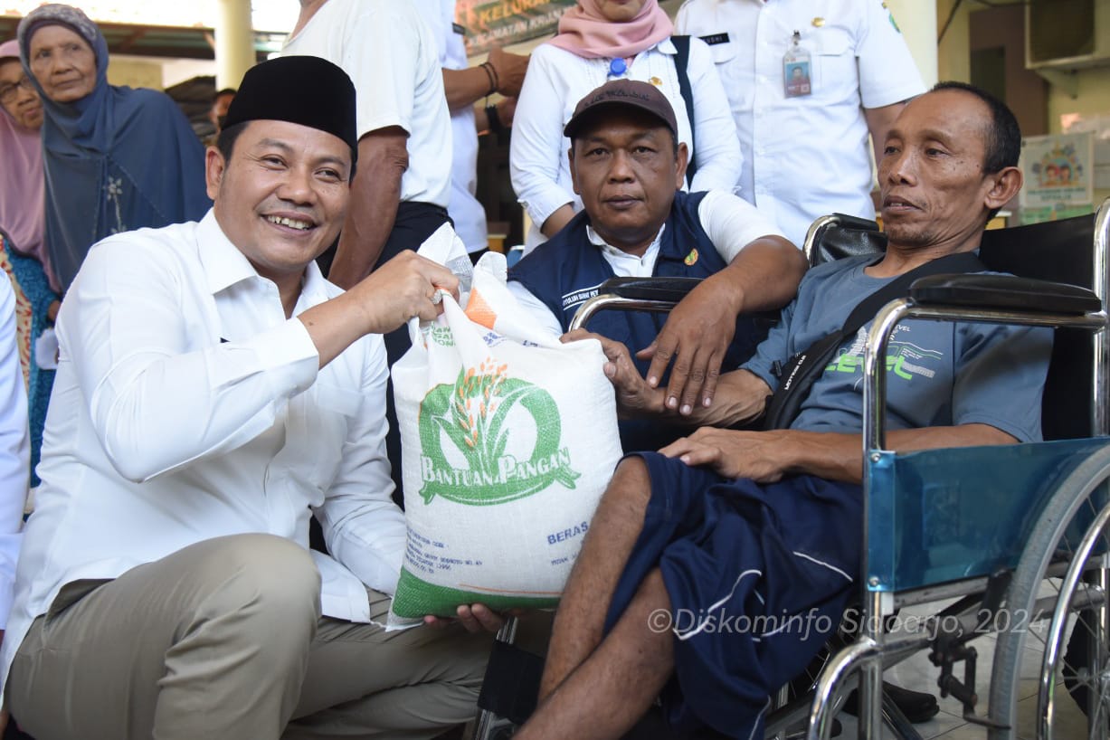 SERAHKAN BANTUAN - Plt Bupati Sidoarjo, Subandi menyerahkan bantuan beras 10 kilogram dari pemerintah pusat untuk warga miskin di sejumlah desa di Kecamatan Krian, Rabu (19/06/2024).