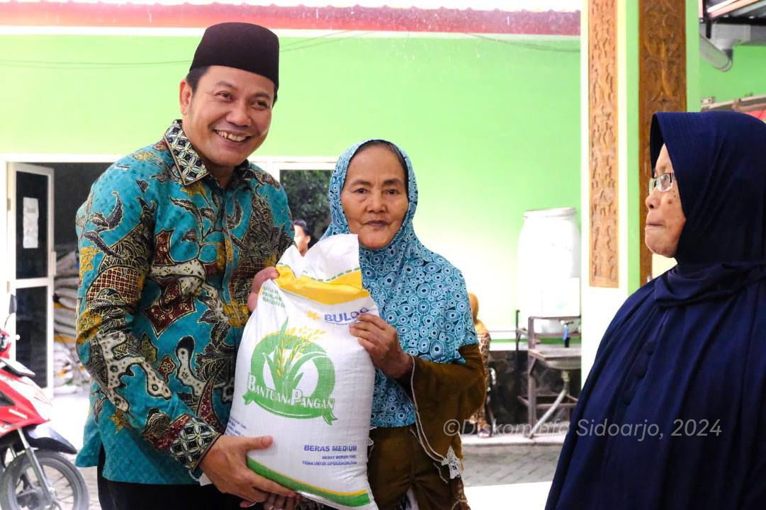SERAHKAN - Plt Bupati Sidoarjo, Subandi menyerahkan bantuan pangan beras 10 kilogram di Kecamatan Taman, Jumat (28/06/2024).