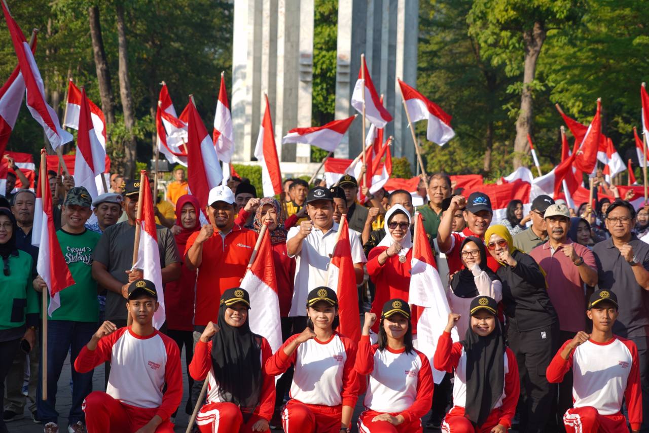 BAGI - Plt Bupati Sidoarjo, Subandi menyerahkan bendera merah putih kepada pada perwakilan organisasi kemasyarakatan di Alun-Alun Sidoarjo, Jumat (19/07/2024). 