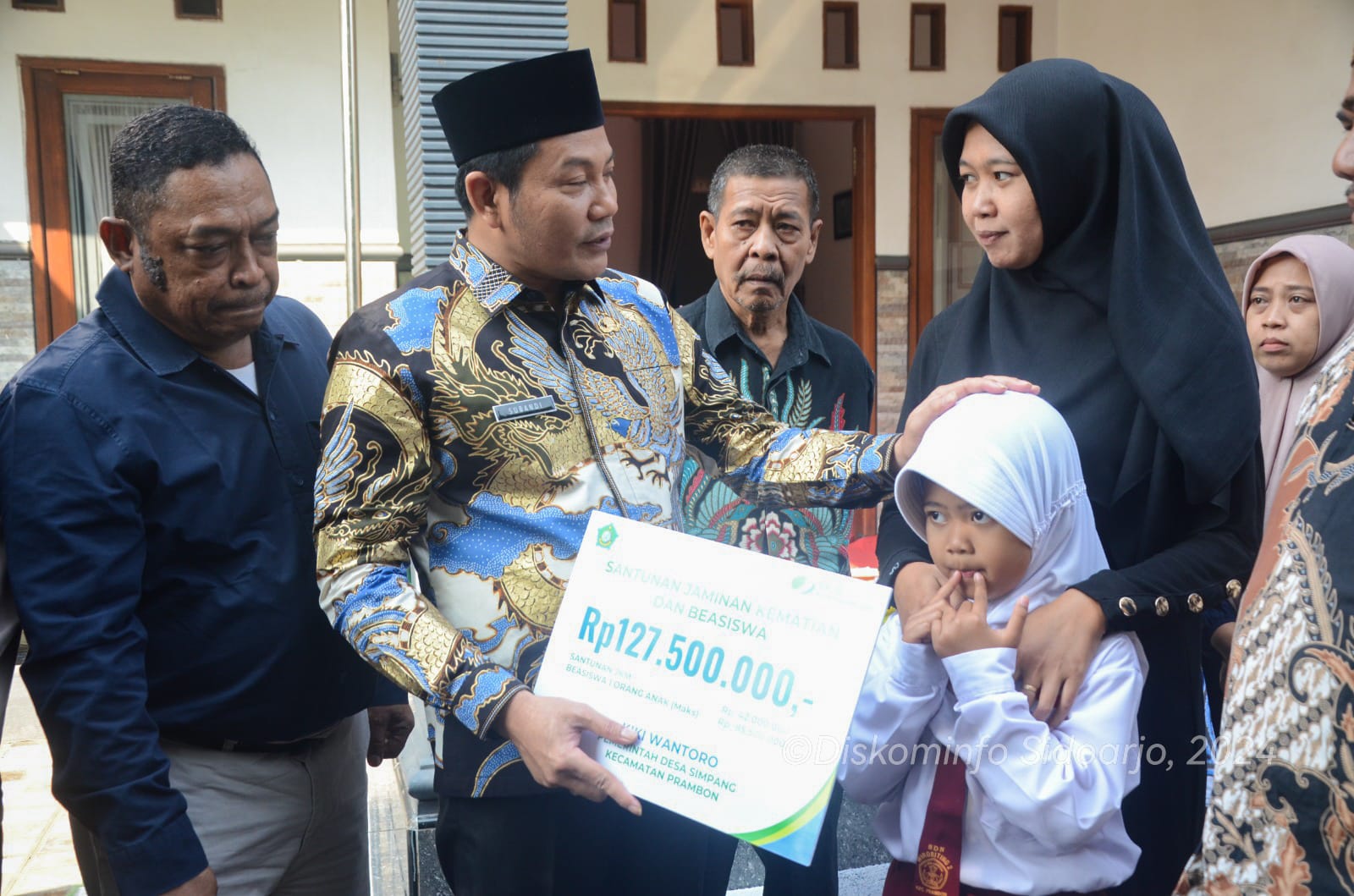 SANTUNAN - Plt Bupati Sidoarjo, Subandi datang didampingi Kepala Kacab BPJS Ketenagakerjaan Krian, Kepala Dinas Sosial menyerahkan santunan ke keluarga perangkat desa di Prambon yang meninggal dunia, Selasa (23/07/2024).