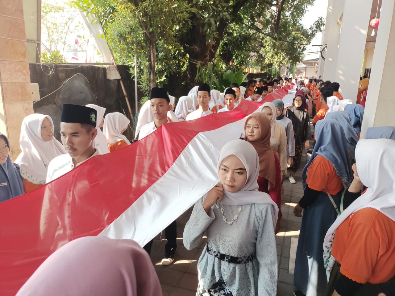 KIRAB - Siswa SMK YPM 8 Sidoarjo kirab bendera merah putih sepanjang 79 meter untuk dibentangkan di lantai 6 sekolah serta Kepala SMK YPM 8 Sidoarjo Dr Kisyanto menanam 79 bibit toga dan sayur di pinggir Sungai Sarirogo, Kecamatan Sidoarjo, Jumat (16/08/2