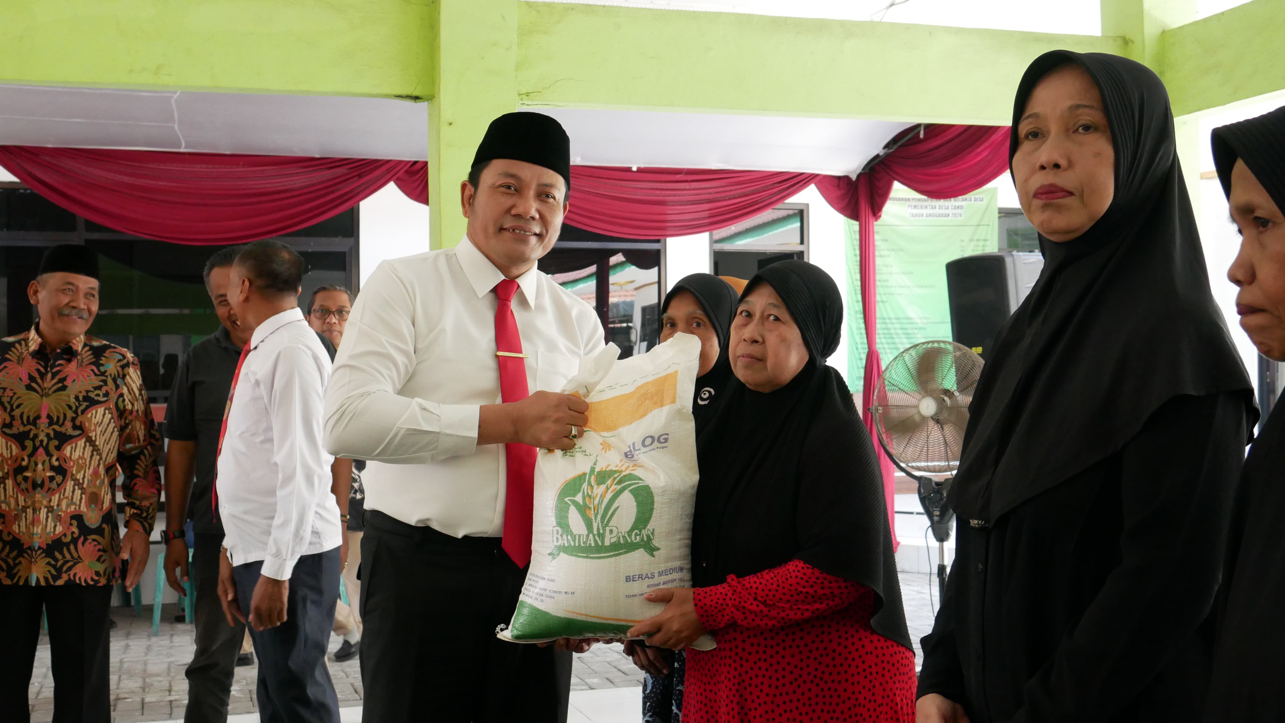 BANTUAN - Plt Bupati Sidoarjo, Subandi meninjau secara langsung penyaluran bantuan pangan beras kepada sebanyak 1.215 Keluarga Penerima Manfaat (KPM) di Desa Kedungpeluk, Wedoroklurak, Bligo dan Desa/kecamatan Candi, Sidoarjo, Jumat (16/08/2024). 