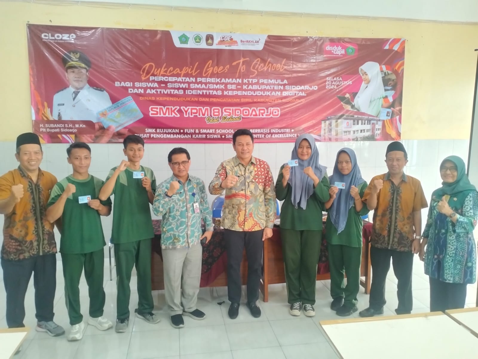 KTP - Plt Bupati Sidoarjo, Subandi didampingi Kepala Dispendukcapil, Redy Kusuma dan Waka Kurikulum, Afthoni ST MT menyerahkan hasil perekaman e KTP 100 siswa siswi SMK YPM 8 Sidoarjo, Selasa (20/08/2024). 