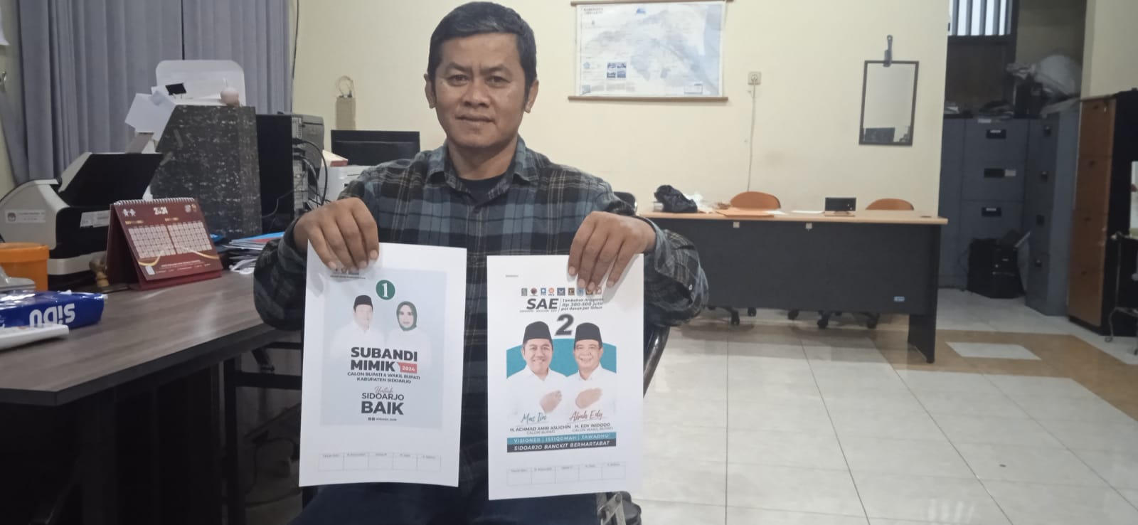 SIAPKAN - Koordinator Divisi Sosdiklih, SDM dan Parmas KPU Sidoarjo, Mokhamad Yasin bersama petugas sekretariat KPU menyiapkan APK dan BK untuk Paslon Pilkada 2024, Rabu (09/10/2024).