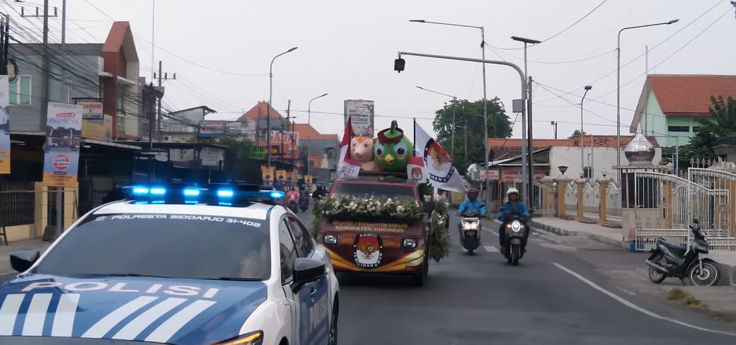 KIRAB - KPU Kabupaten Sidoarjo menggelar kirab Maskot Guk KASIJO bersama Si JALIH berangkat dari Kantor KPU Sidoarjo di JL Raya Cemengkalang Sidoarjo menuju Surabaya untuk diserahkan ke KPU Jatim, Rabu (23/10/2024).