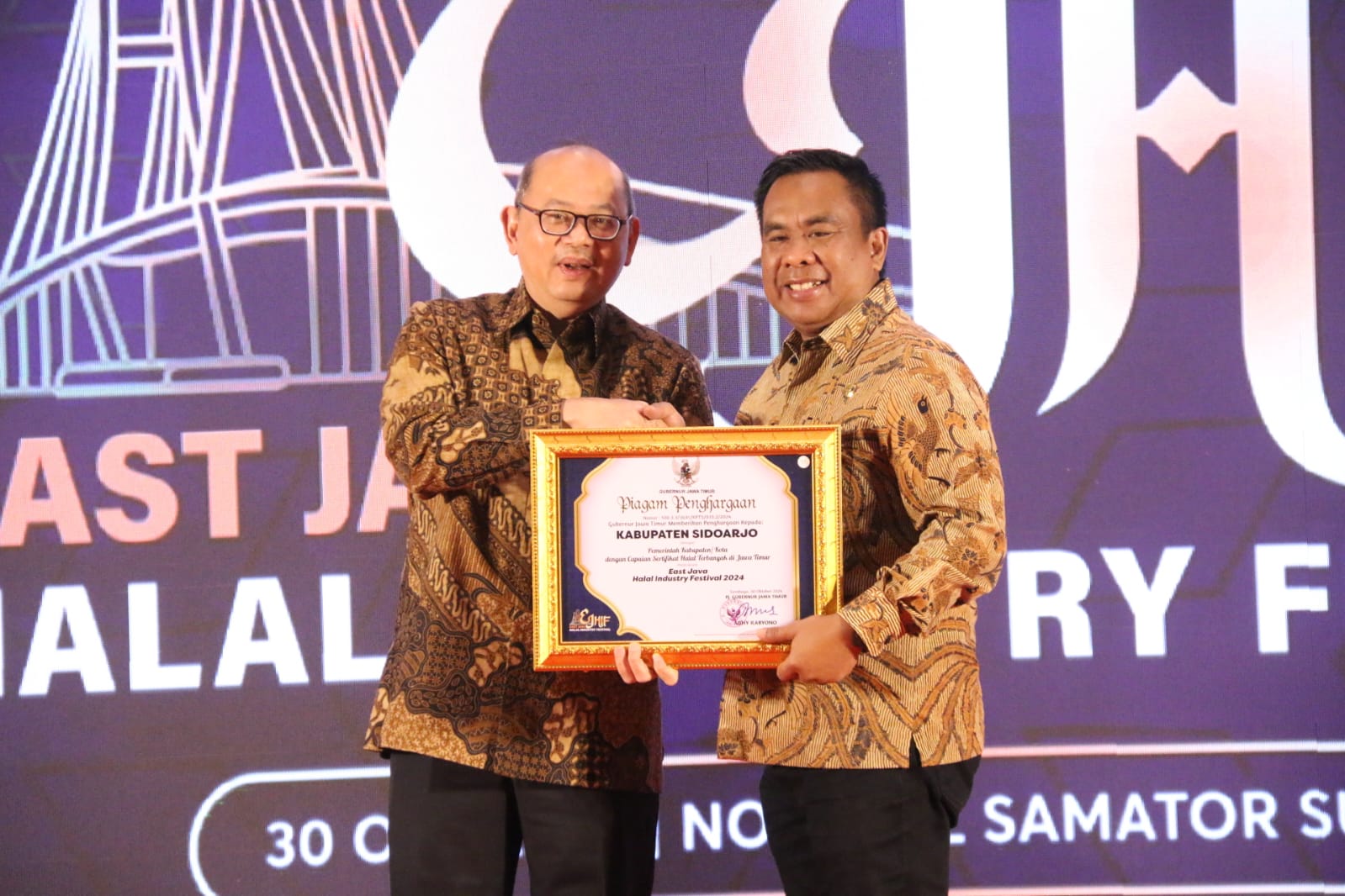 TERIMA - Sidoarjo meraih penghargaan kabupaten/kota sertifikat halal terbanyak dari Gubernur Jatim diterima Pjs Bupati Muhammad Isa Anshori dari Pj Sekda Bobby Soemiarsono di East Java Halal Industry Festival 2024 di Hotel Novotel, Rabu (30/10/2024).