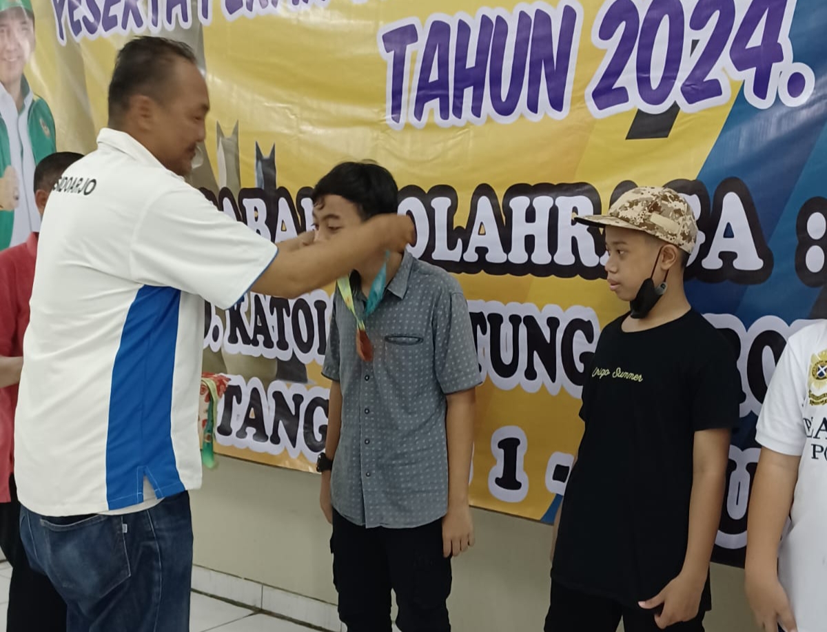 JUARA - Pengurus KONI Sidoarjo, Ucok S menyerahkan tropi dan uang pembinaan kepada M Aryan Dhiazafri Ar-Rayiid yang meraih juara 3 di olahraga catur antar atlet di Pekan Olahraga Kabupaten (PORKAB) Sidoarjo, Kamis (01/08/2024).
