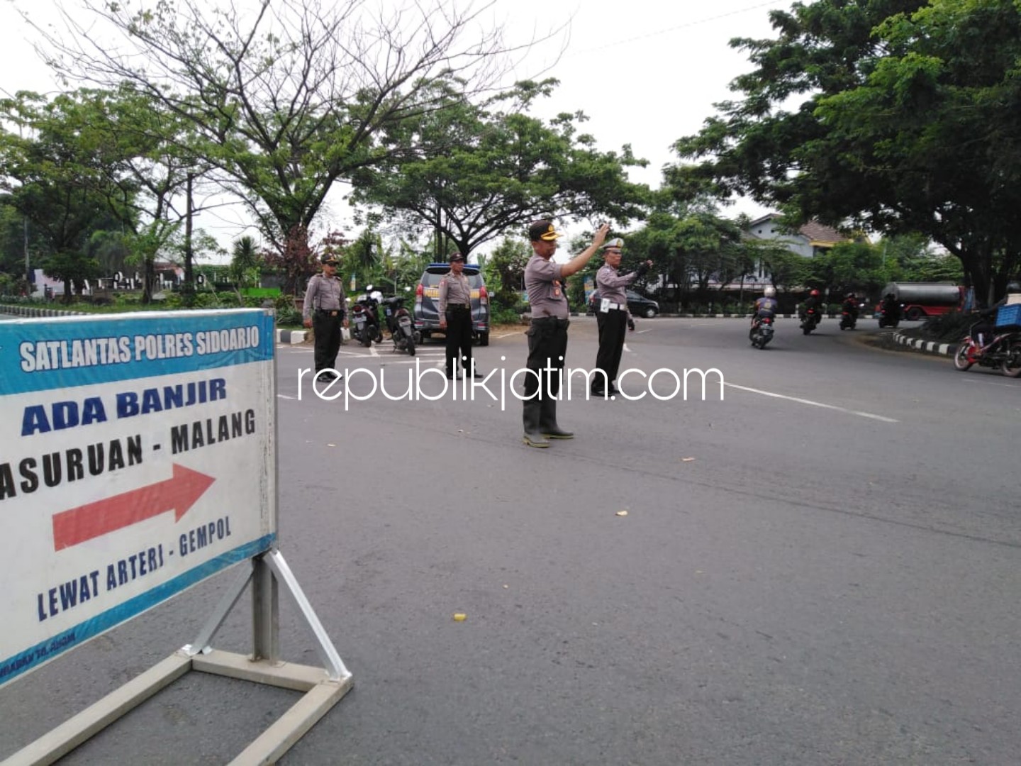PENGALIHAN ARUS - Kapolsek Tanggulangin Kompol Hardyantoro saat mengatur arus lalu lintas di bundaran Desa Ketapang, Kecamatan Tanggulangin agar JL Raya Porong Lama tidak macet dan motor tidak menerobos banjir, Rabu (09/01/2019).