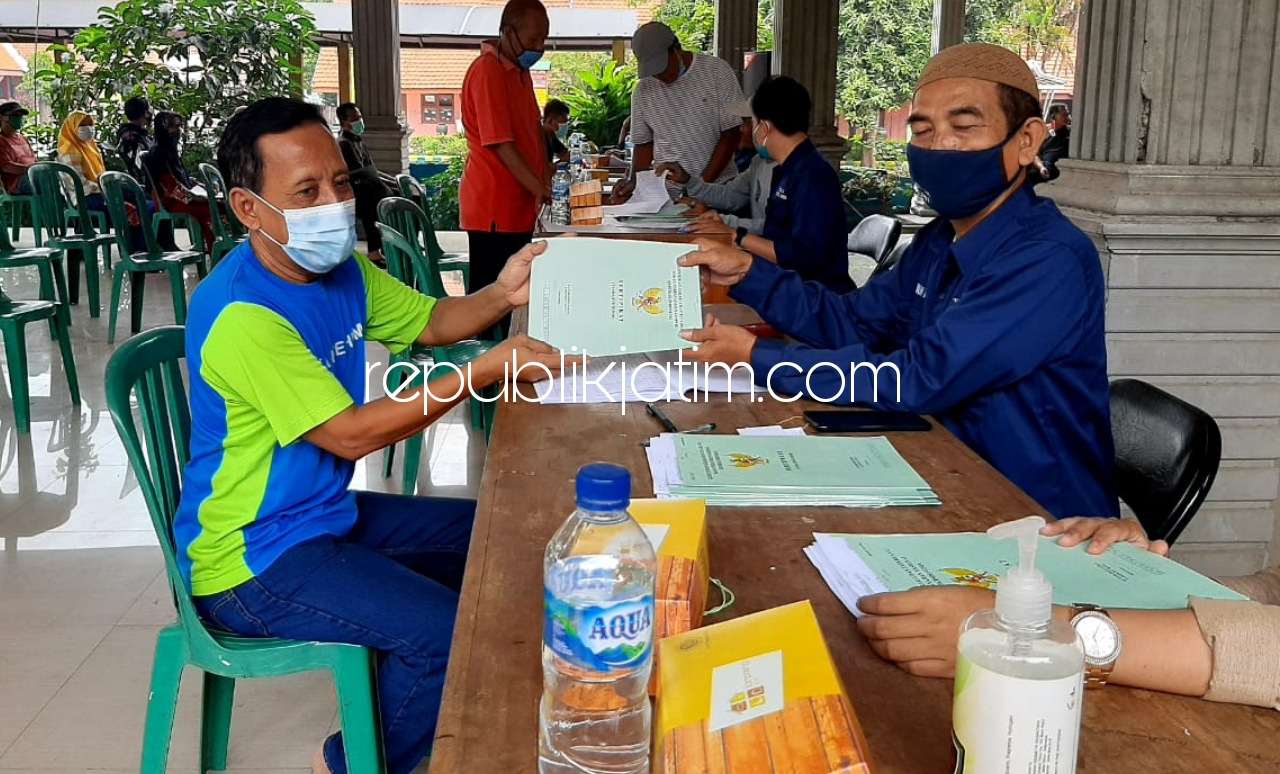 BAGIKAN - Salah satu warga Desa Tanggul, Kecamatan Wonoayu, Sidoarjo Narko menerima sertifikat tanah kering tanpa stempel BPN Sidoarjo di Pendopo Kantor Desa setempat, Minggu (10/01/2021). 