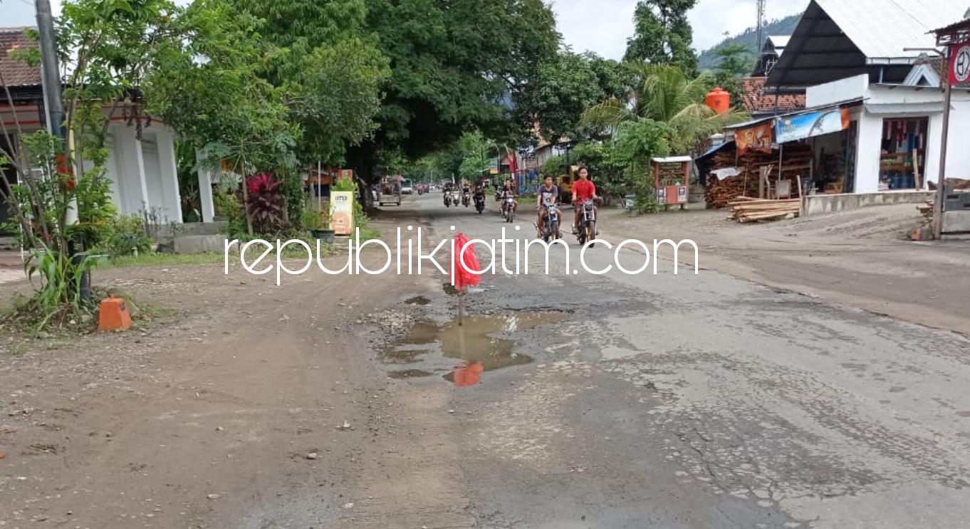 TANDA - Warga memberi tanda pada kubangan di JL Raya Desa/Kecamatan Bungkal, Ponorogo agar pengguna jalan tak terjebak di jalan berlubang itu terutama saat lubang dipenuhi genangan air, Sabtu (16/01/2021).