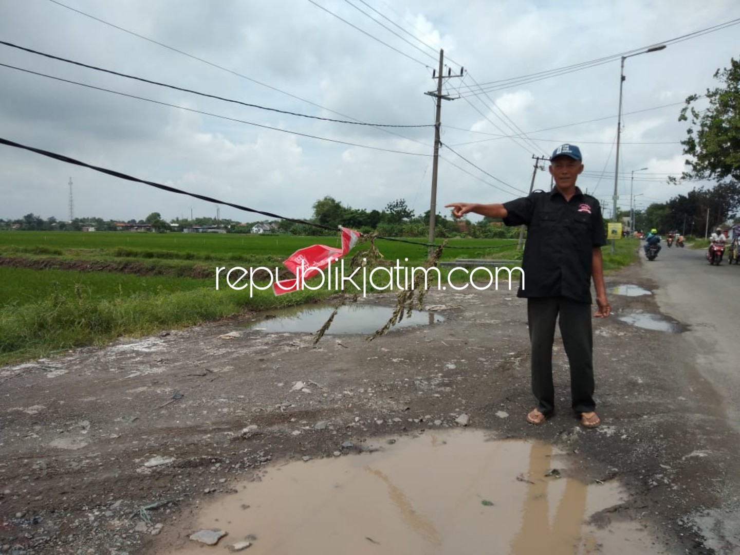 NGELEWER - Warga Desa Sawocangkring, Kecamatan Wonoayu, Sidoarjo menunjukkan kabel PJU yang ngelewer (menggelantung) mengganggu haluan kendaraan besar perusahaan, Sabtu (26/01/2019).
