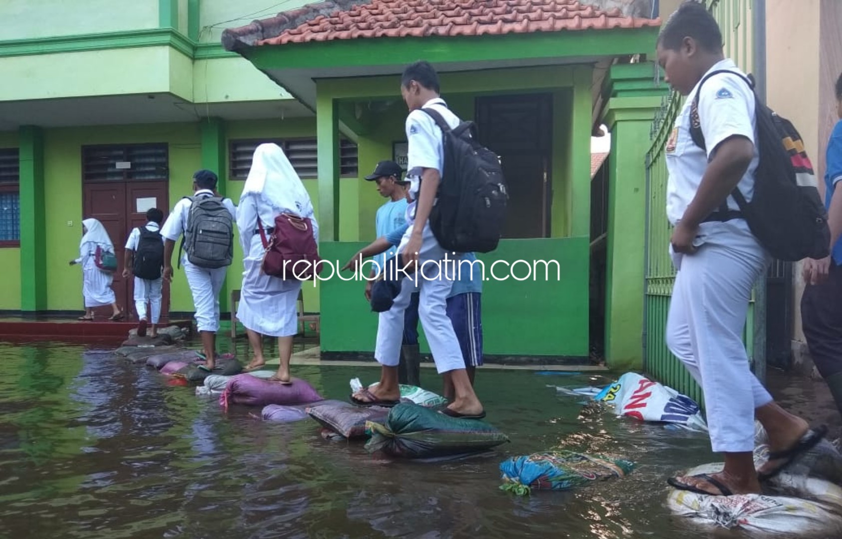 BANJIR - Para siswa dan siswi SMPN 2 Tanggulangin di Desa Kedungbanteng, Kecamatan Tanggulangin, Sidoarjo memaksa tetap sekolah meski 7 ruang kelas dan lainnya terendam banjir, Senin (27/01/2020).