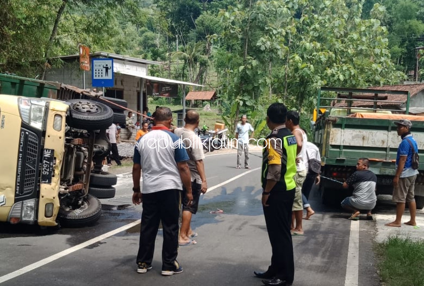 TERGULING - Sejumlah petugas Polsek Pulung mengatur arus lalu lintas di TKP truk bermuatan asbes yang terguling di JL Raya Ponorogo - Pacitan, Jumat (31/01/2020). 