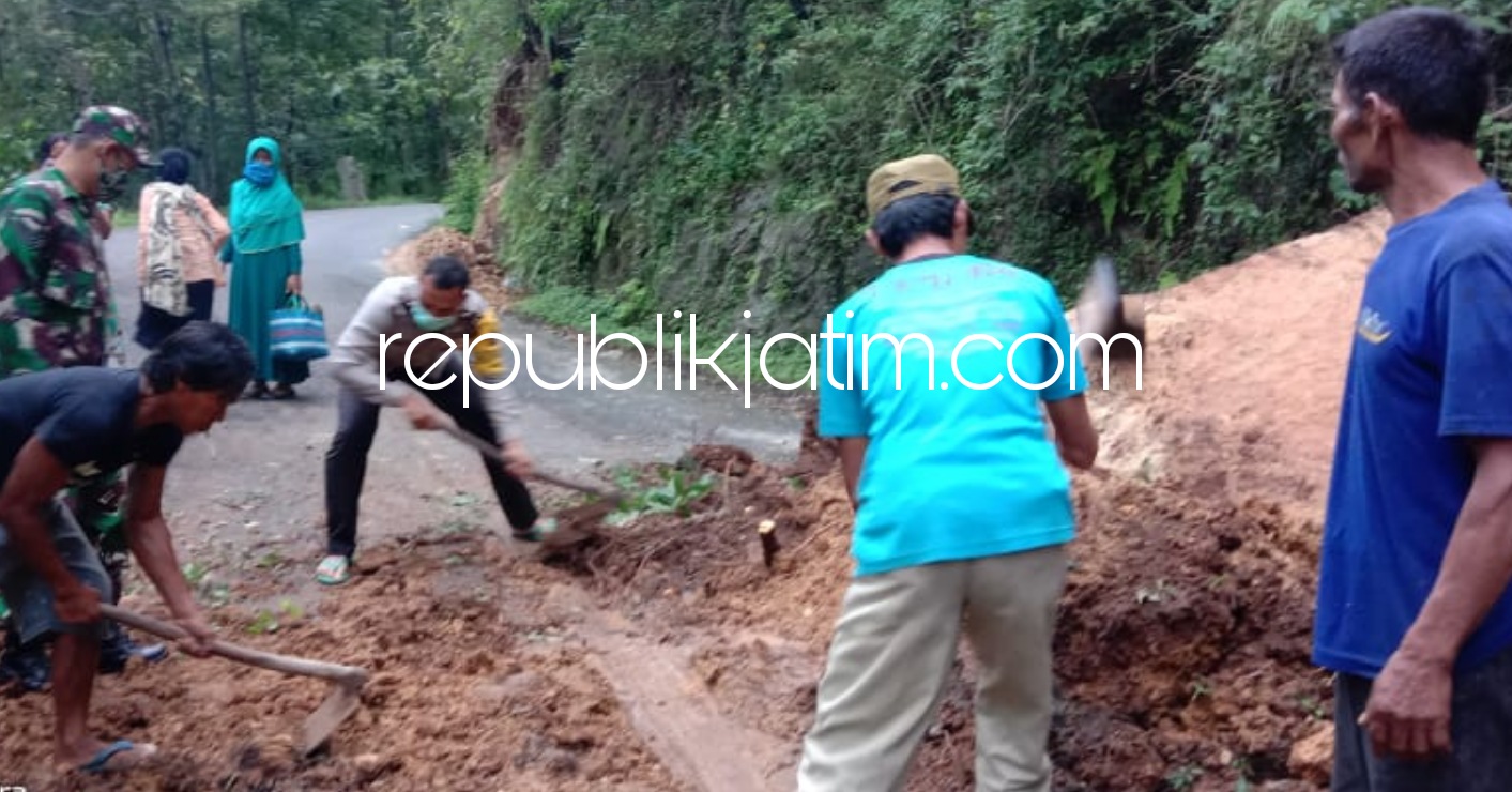 LONGSOR - Petugas Polsek Bungkal bersama Pemdes dan warga Pelem mengevakuasi dan membersihkan material longsor dan memotong pohon tumbang yang menutup jalan raya Bungkal - Ngrayun, Ponorogo Minggu (07/02/2021).