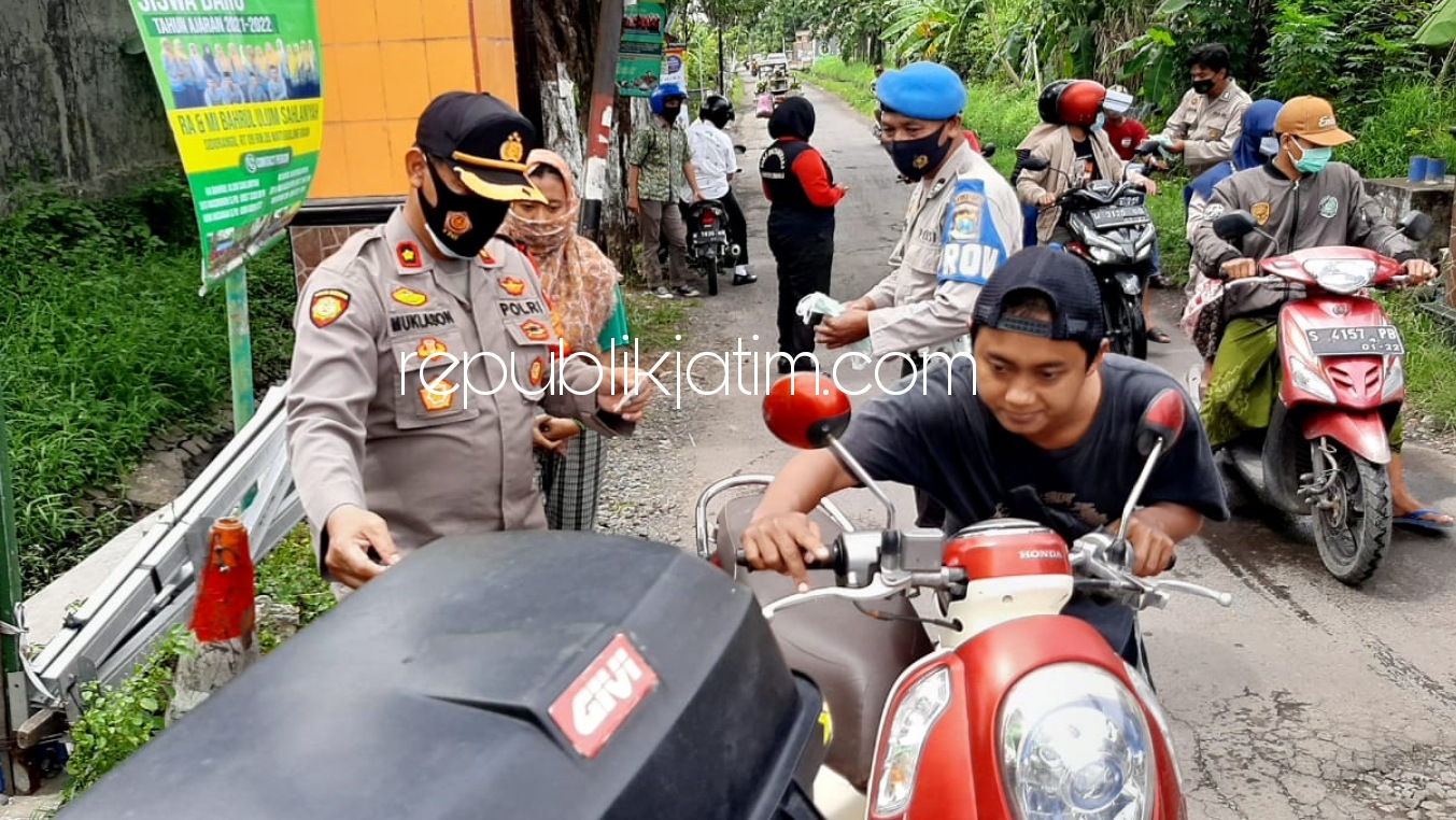 BAGI MASKER - Sejumlah anggota Polsek Krian bersama Satpol PP membagi masker di pos check point pintu masuk Desa Sidomojo, Kecamatan Krian, Sidoarjo saat PPKM mikro, Selasa (09/02/2021).