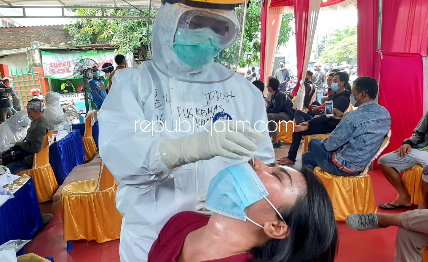 RAPID ANTIGEN - Warga Trenggalek dan Gresik dibawa Ambulance Krian untuk dikirim ke ruang isolasi serta Kapolsek Krian dan Kapolsek Prambon memeriksa data nama hasil rapidnya reaktif saat rapid antigen di By Pass Krian Sidoarjo, Jumat (12/02/2021).