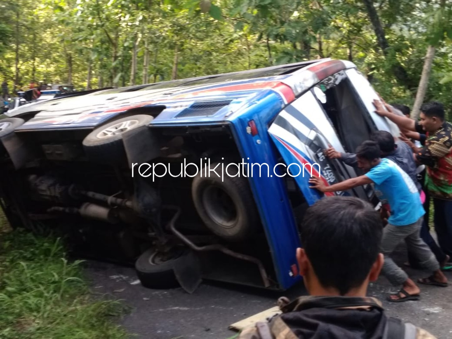 DORONG - Belasan warga dan pengguna jalan mendorong minibus yang terguling dan menutup JL Raya Bungkal - Ngrayun tepatnya di tikungan Clonthang Desa Pelem, Kecamatan Bungkal, Ponorogo, Senin (11/02/2019).
