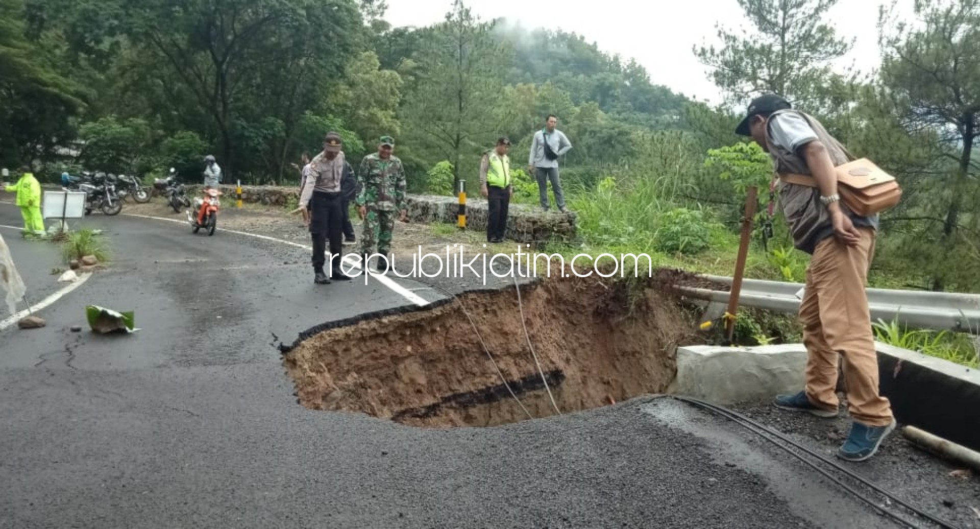 AMBLES - Sejumlah anggota Polsek dan Koramil Slahung sedang memasang police line di jalan ambles di Desa Wates, Kecamatan Slahung, Ponorogo, Kamis (20/02/2020).