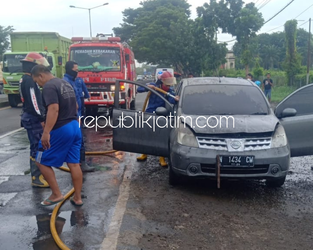 TERBAKAR - Sebuah mobil Grand Livina yang terbakar dipadamkan petugas Pemadam Kebakaran (PMK) dibantu warga sekitar JL Raya By Pass Krian, Sidoarjo, Sabtu (20/02/2021). 
