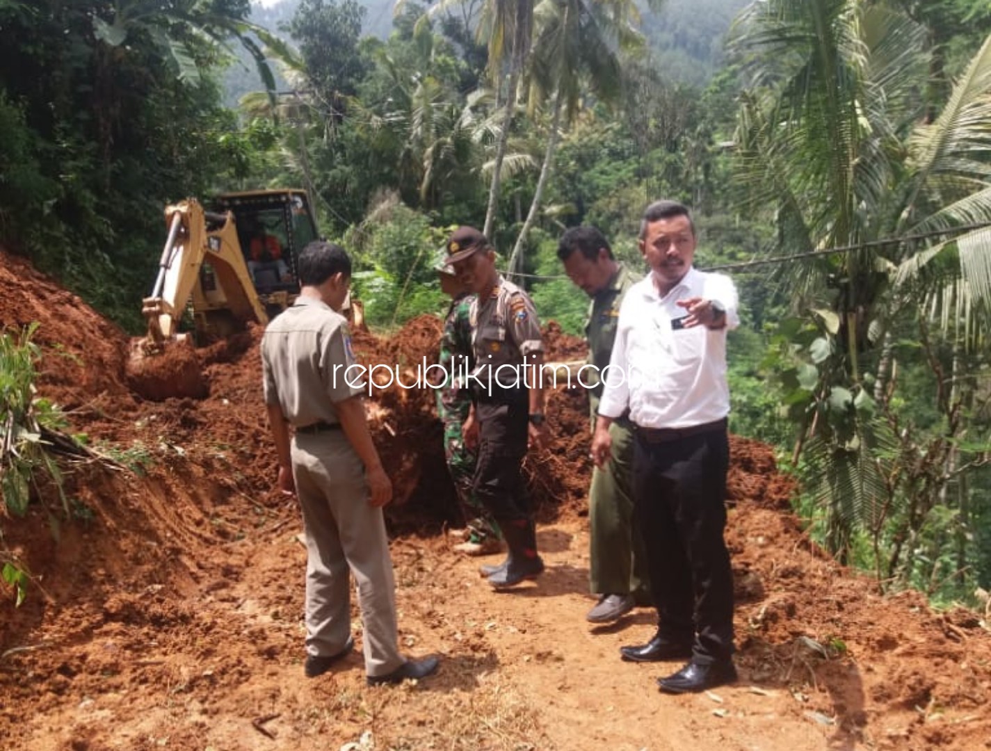 EVAKUASI - Petugas mengevakuasi longsor yang tutup badan jalan antar dusun di Desa/Kecamatan Ngrayun, Ponorogo, Senin (02/03/2020).
