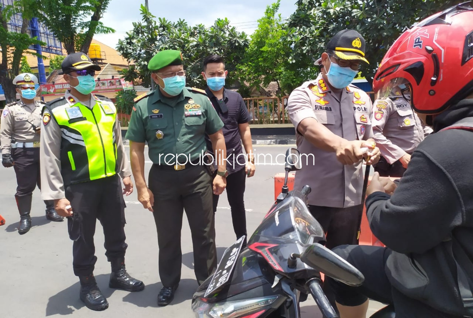 SEMPROTKAN - Kapolresta Sidoarjo, Kombes Pol Sumardji menyemprotkan hand sanitizer dan membagikan masker kepada para pengguna jalan yang melintas di depan Pos Lantas Waru bersama anggota Koramil Waru, Minggu (22/03/2020).