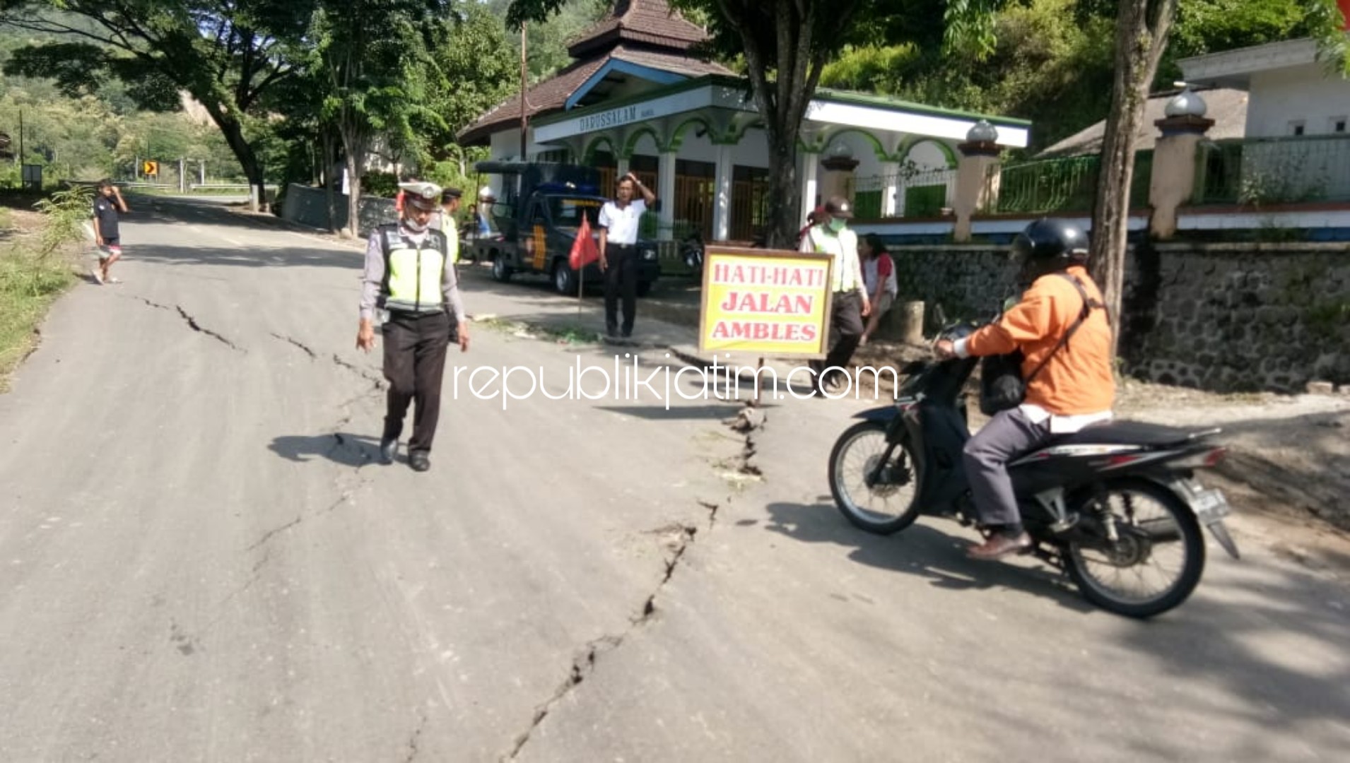 RETAK - Sejumlah petugas Polsek Slahung memasang rambu peringatan di Jalan Raya Ponorogo-Pacitan, Dusun Bukul, Desa Wates, Kecamatan Slahung Ponorogo yang retak dan ambles akibat curah hujan tinggi, Selasa (24/03/2020) dini hari.