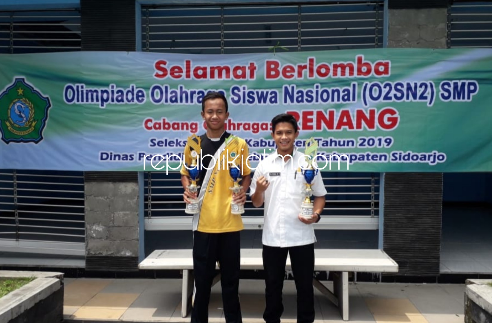 JUARA - Latiful Muyassar siswa kelas 8 SMPN 1 Sidoarjo yang merupakan atlit muda renang Sidoarjo berfoto bersama gurunya seusia menjadi juara umum Olimpiade Olahraga Siswa Nasional (O2SN) cabang olahraga renang berhak mewakili tingkat Propinsi Jatim.