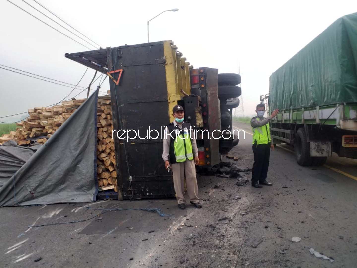 TERGULING - Petugas Lantas Polsek Porong mengalihkan arus ke jalur lambat Arteri Porong lantaran adanya truk bermuatan kayu yang terguling dan menutup jalur Alteri Porong, Selasa (31/03/2020).