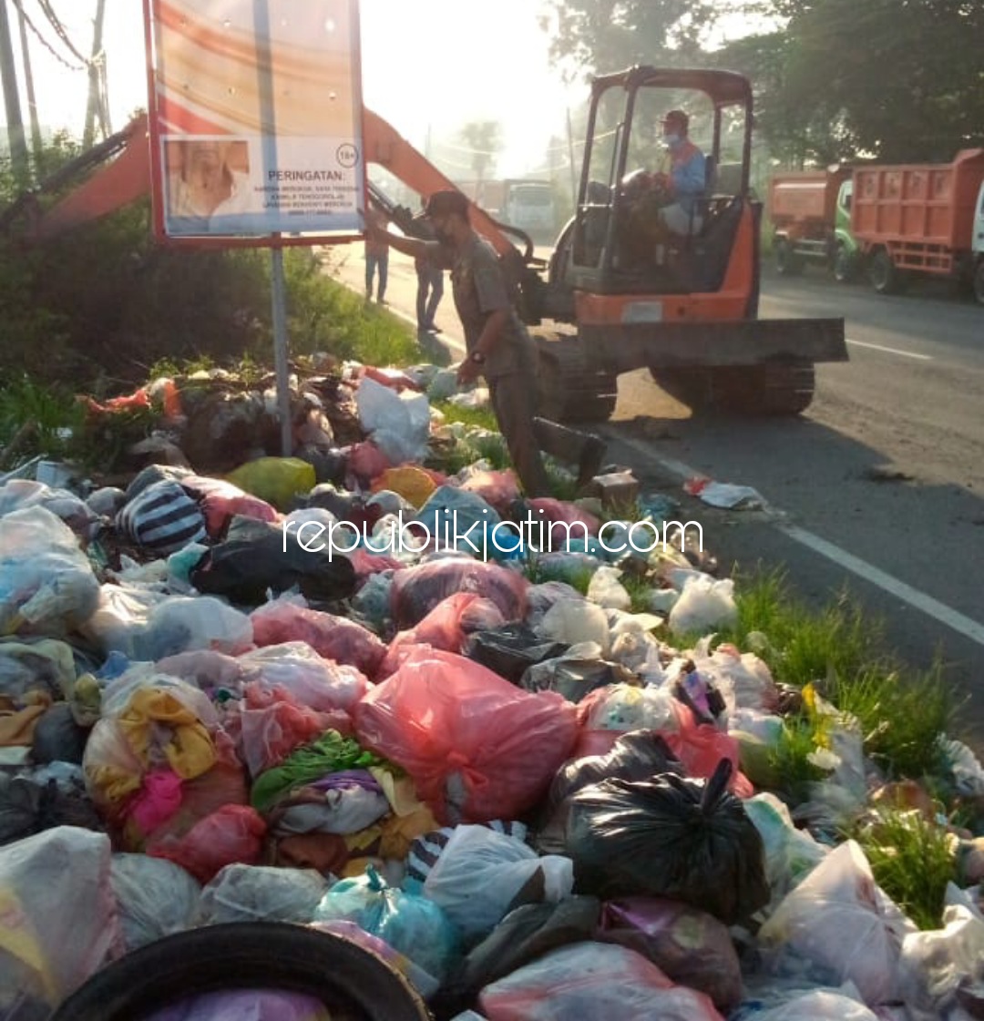 DIANGKUT - Tumpukan sampah yang ada di tepi JL Raya Mojokerto-Surabaya Desa Kemangsen, Kecamatan Balongbendo, Sidoarjo dikeruk eksavator dan diangkut truk DLHK, Minggu (18/4/2021). 