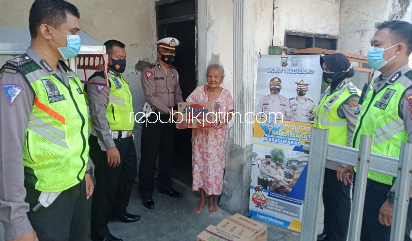 BAGI - Kasat Lantas Polresta Sidoarjo, Kompol Wikha Ardilestanto membagikan zakat berupa sembako kepada masyarakat, seperti Ny Adjanah, seorang janda di Kelurahan Magersari, Kecamatan Sidoarjo, Rabu (21/04/2021).