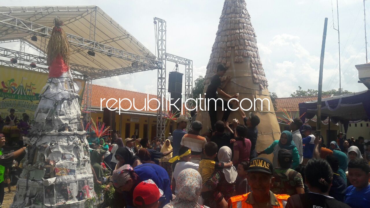 REBUTAN - Ribuan warga Desa Mulyodadi, Kecamatan Wonoayu, Kabupaten Sidoarjo rebutan 2 tumpeng berukuran besar di halaman kantor balai desa setempat sebagai wujud rasa syukur, Sabtu (21/04/2018).