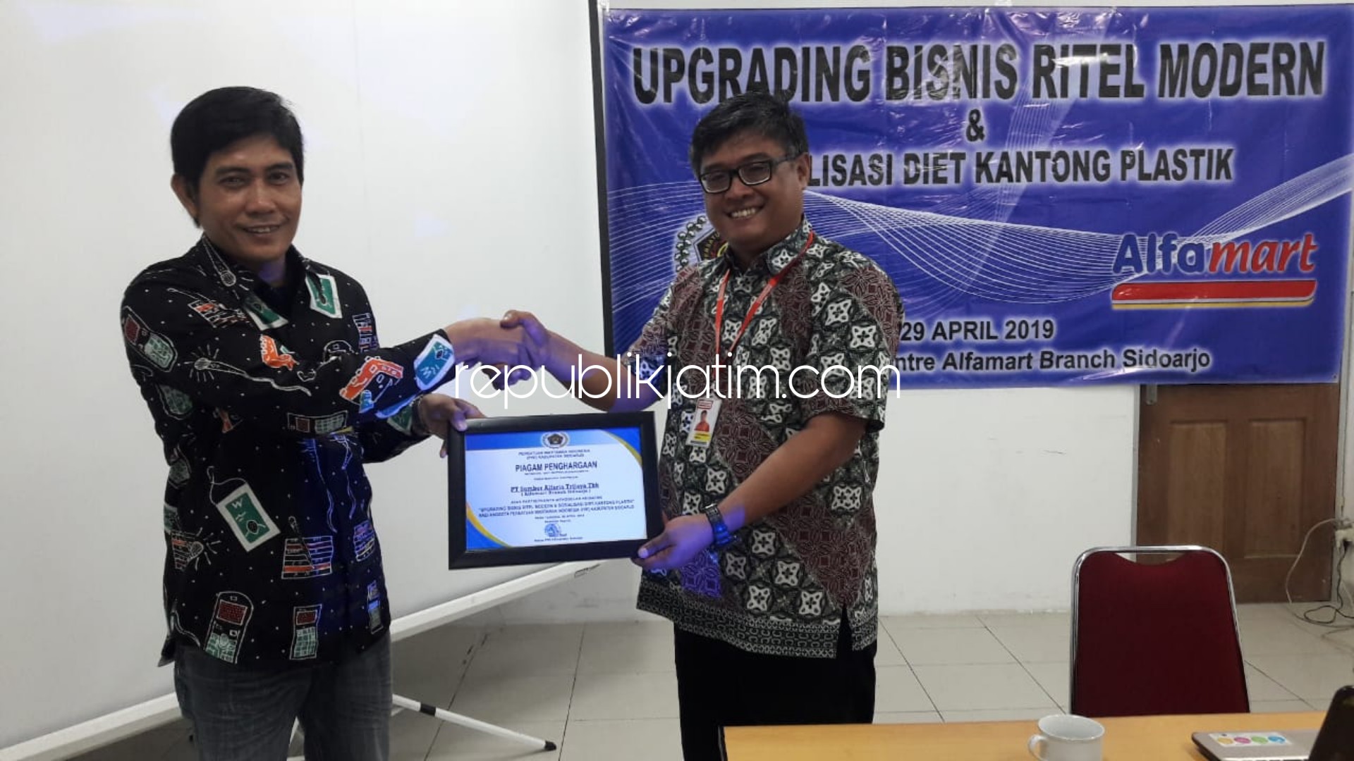 CINDERA MATA - Ketua PWI Sidoarjo, Abdul Rouf menyerahkan cinderita mata berupa piagam penghargaan kerjasama kepada Branch Manager Alfamart Sidoarjo, Andon Swasono Putro, Senin (29/04/2019).