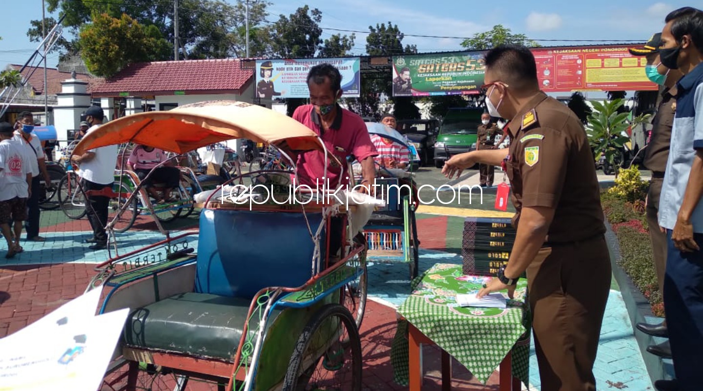 ANTRE - Ratusan tukang becak dengan tertib antre memenuhi halaman kantor Kejaksaan Negeri (Kejari) Ponorogo untuk menerima bingkisan lebaran, Senin (10/05/2021). 