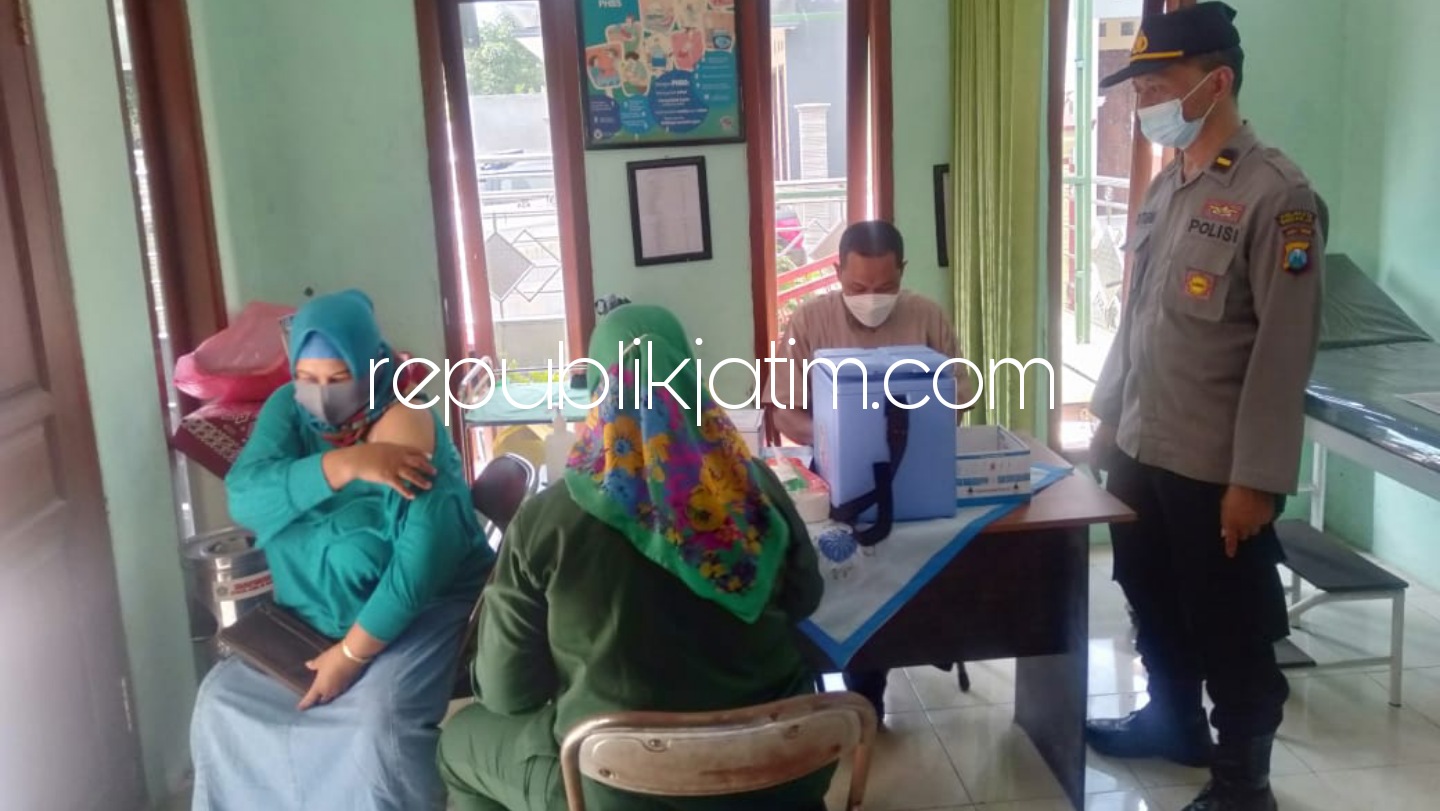 VAKSIN - Anggota Polsek Krembung berjaga saat pelaksanaan vaksin bagi warga Desa Waung, Kecamatan Krembung, Sidoarjo, Jumat (21/05/2021).