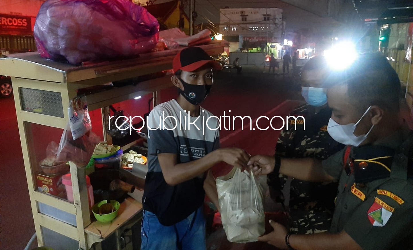 BORONG - Kasatkoryon Banser Krian, Fitrul Rosyidin saat memborong Tahu Tek milik Gunawan karena terjebak di dalam pos Penyekatan PPKM Darurat di Krian, Rabu (07/07/2021) malam. 