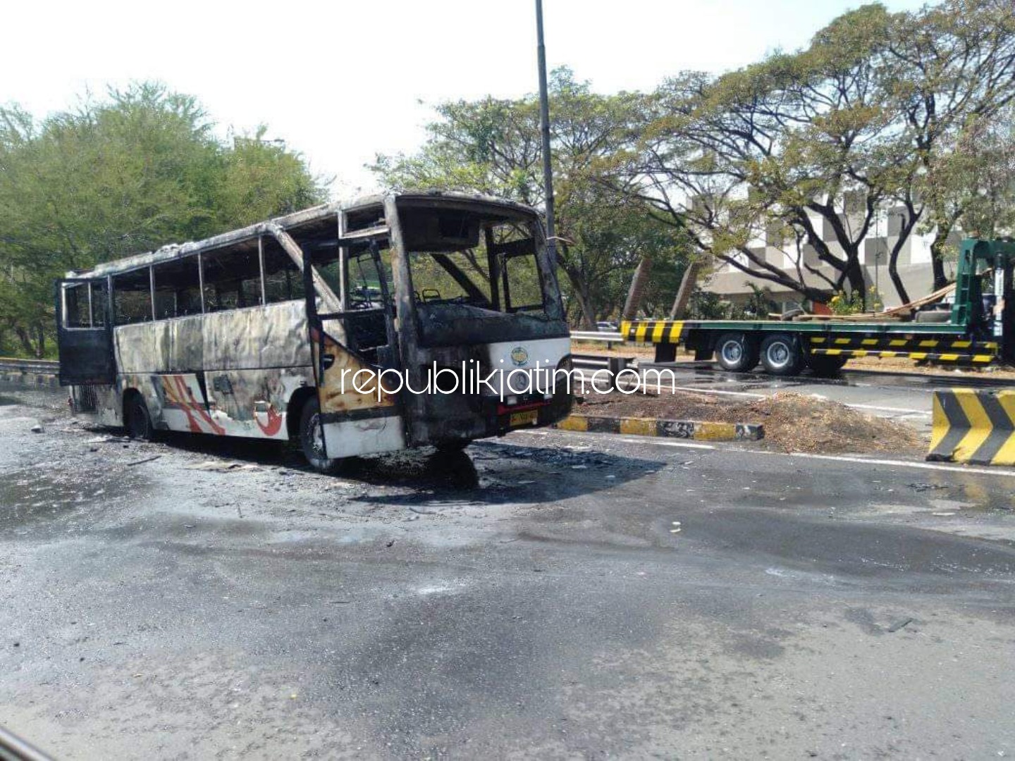TERBAKAR - Sejumlah petugas PJR Jatim II berupaya mengevakuasi kerangka bus AKAS bernopol N 7046 US di JL Tol Sidoarjo - Porong tepatnya di pintu masuk, Minggu (21/07/2019).
