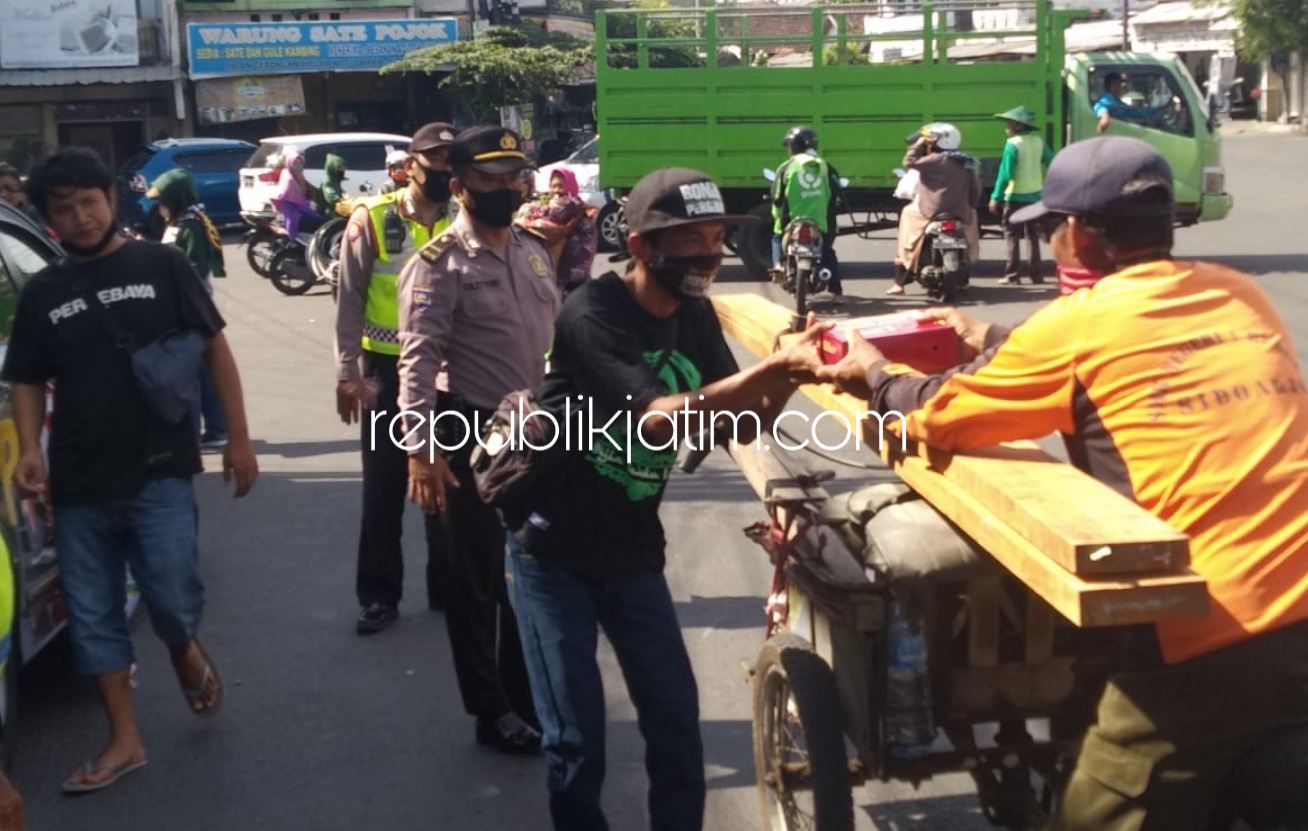 BERBAGI - Sejumlah anggota Polsek Waru dan bonek membagikan masker dan nasi bungkus kepada pengguna jalan yang melintas di JL Letjen Suprapto, Wadungasri, Kecamatan Waru, Sidoarjo, Jumat (24/07/2020). 