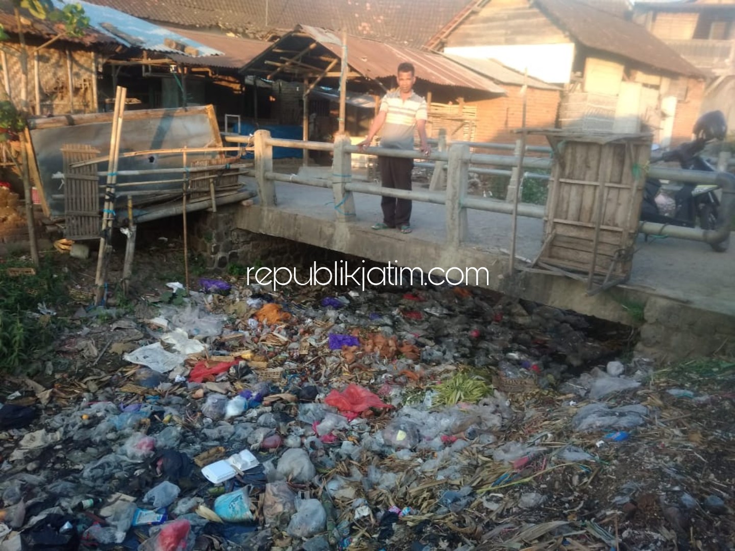 MENUMPUK - Busrianto menunjukkan kondisi sampah yang menumpuk di sepanjang sungai yang berada di samping Pasar Wage, Jetis, Ponorogo, Kamis (25/07/2019).