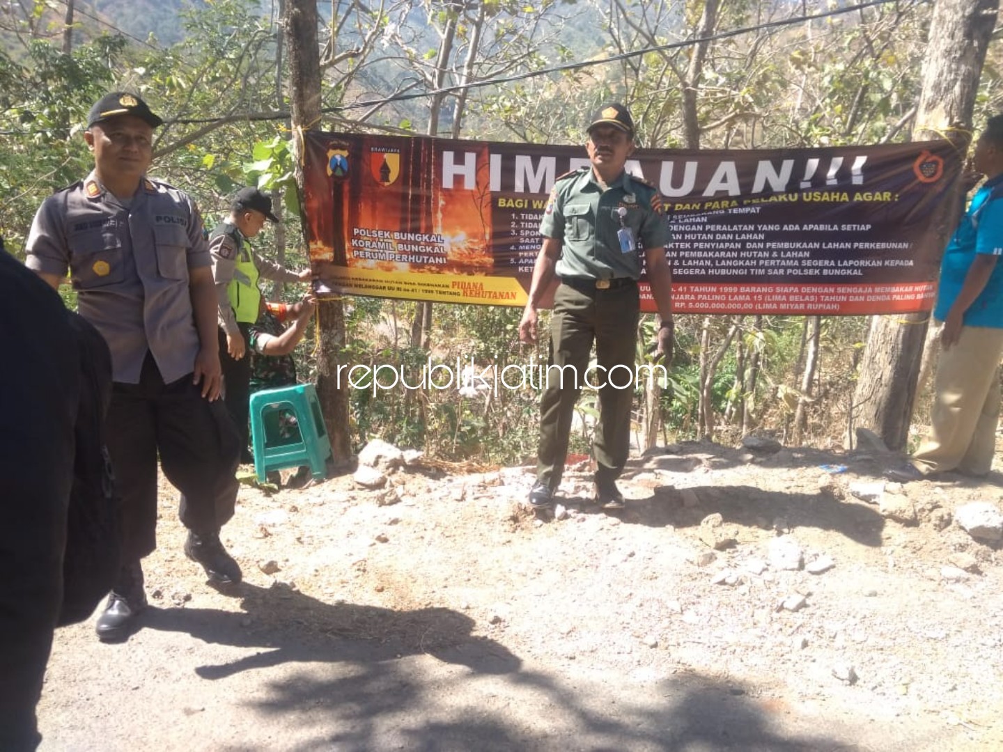 PERINGATAN - Kapolsek Bungkal, AKP Joko Suseno memimpin pemasangan spanduk larangan pembakaran hutan dan ancaman hukumannya di perbatasan hutan Desa Pelem dan Munggu, Kecamatan Bungkal, Ponorogo, Jumat (09/08/2019).