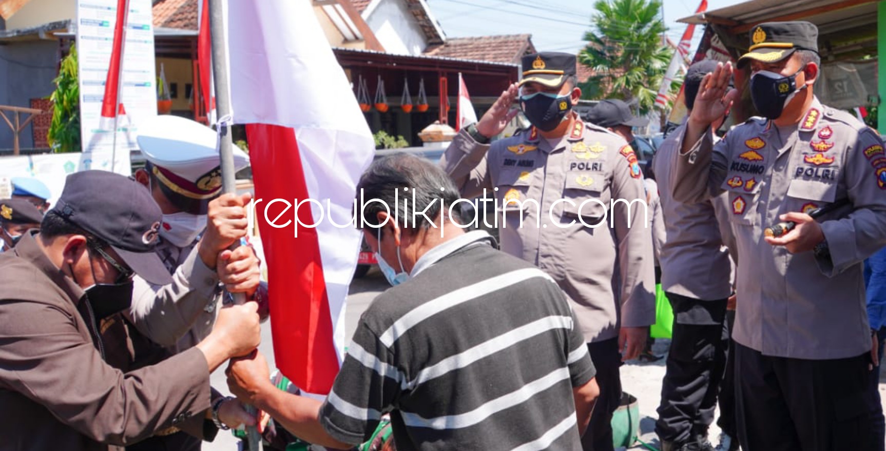 BENDERA - Kapolresta Sidoarjo, Kombes Pol Kusumo Wahyu Bintoro membagi bansos 200 paket sembako dan bendera merah putih untuk warga Desa Kedungcangkring, Kecamatan Jabon terdampak pandemi Covid-19 dan perpanjangan PPKM level 4, Rabu (11/08/2021).