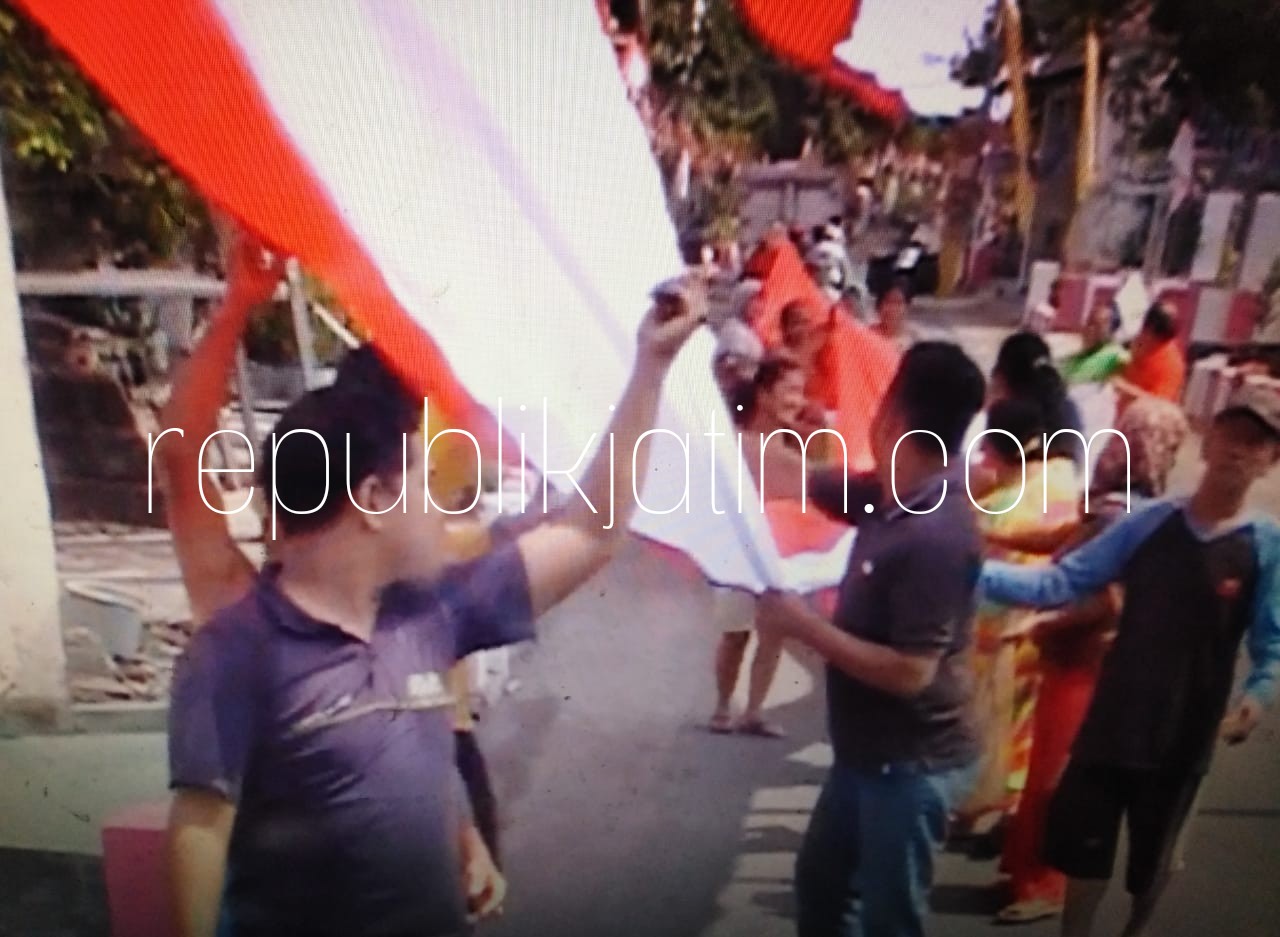 BENDERA RAKSASA - Puluhan warga Desa Keper, Kecamatan Krembung, Sidoarjo sibuk memasang bendera raksasa berukuran 350 meter dengan lebar 3 meter, Rabu (15/08/2018).