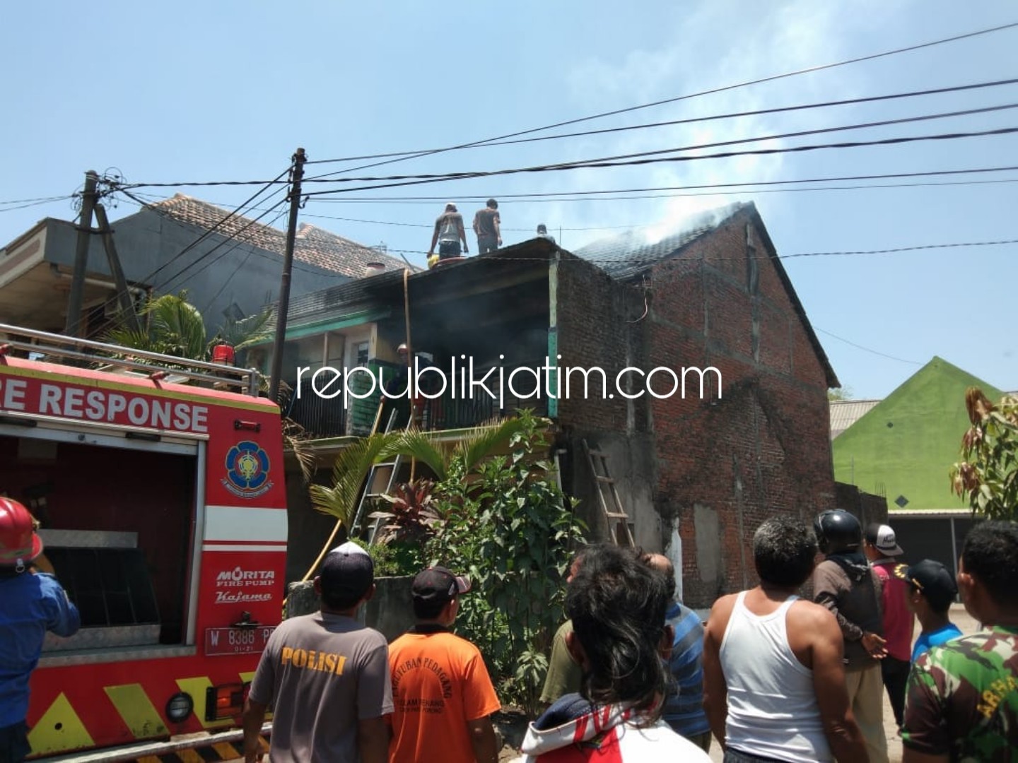 TERBAKAR - Kondisi rumah Slamet warga Desa Candipari, Kecamatan Porong, Sidoarjo saat terbakar mengeluarkan asap putih dipadamkan warga dan petugas PMK, Senin (24/09/2018).